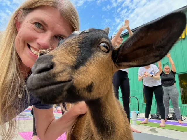 girl poses for selfie with goat at goat yoga