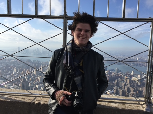 young man stands on viewing deck of the Empire State Building just named the number 1 attraction in the world